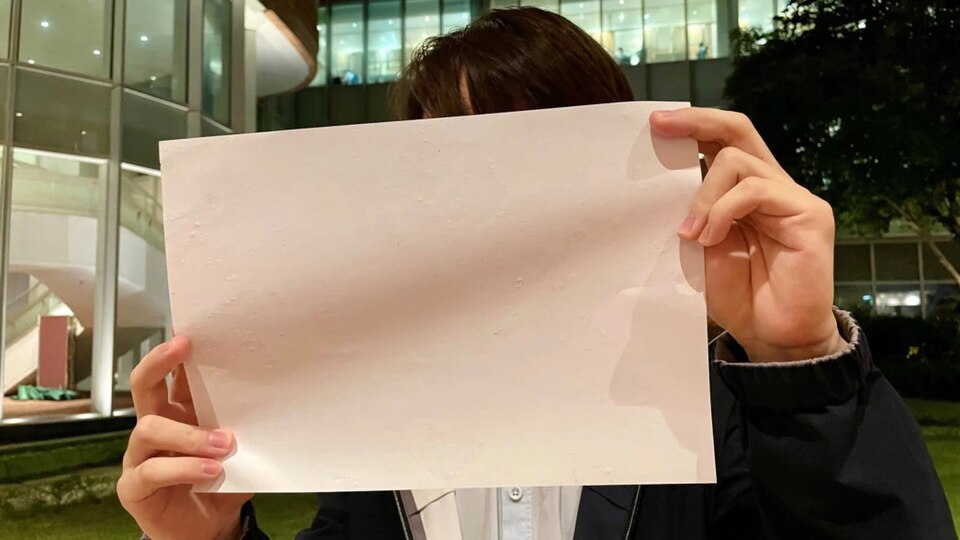 University students holding blank white A4 sheets of paper during candlelight vigils in late November 2022 mourning victims of the Urumqi apartment fire.
